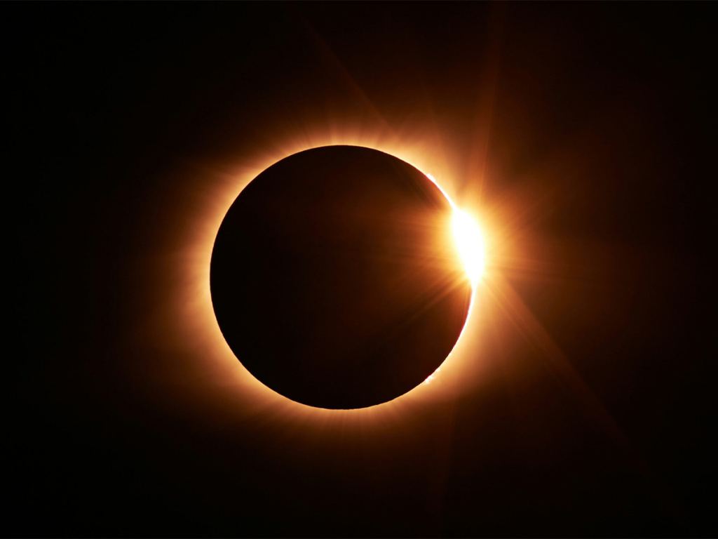 A solar eclipse with the moon almost covering the sun, leaving a bright ring and a burst of light on one edge against a dark sky. - PsychDiscouse