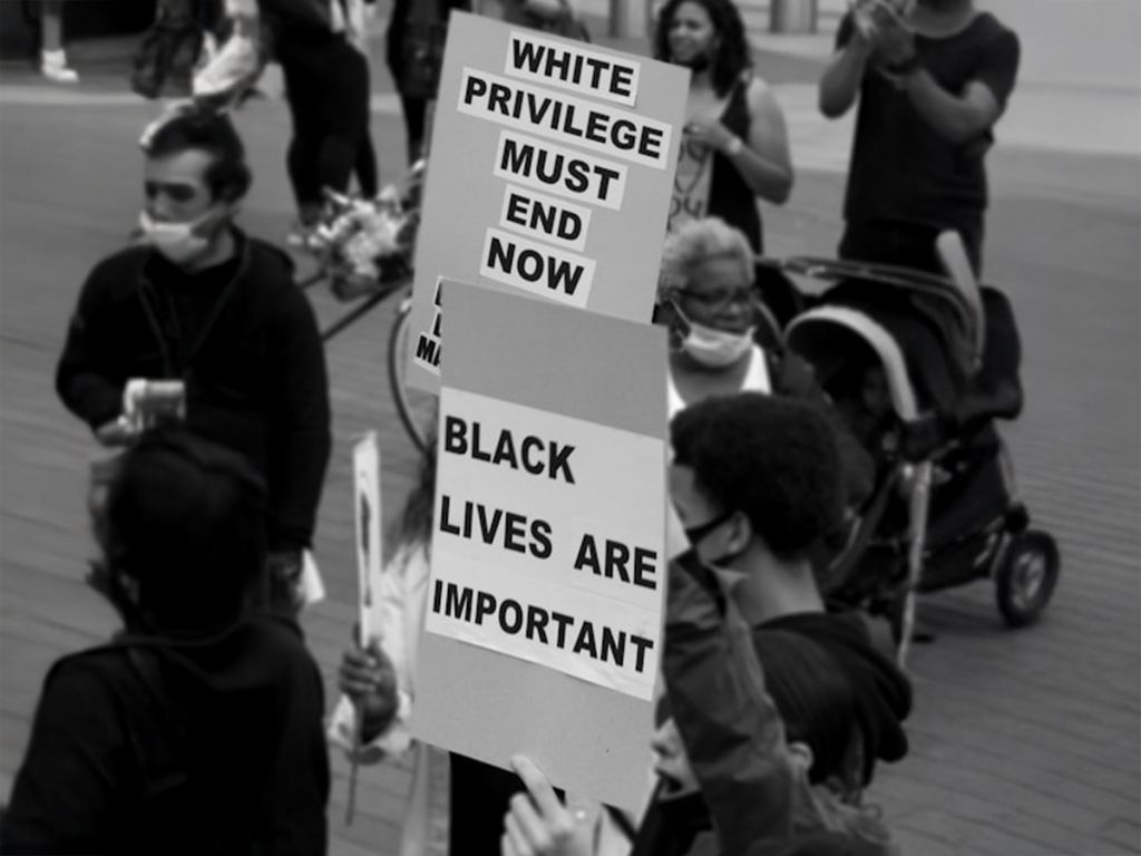 Protesters hold signs reading "WHITE PRIVILEGE MUST END NOW" and "BLACK LIVES ARE IMPORTANT" during a public demonstration. - PsychDiscouse