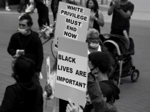 Protesters hold signs reading "WHITE PRIVILEGE MUST END NOW" and "BLACK LIVES ARE IMPORTANT" during a public demonstration. - PsychDiscouse