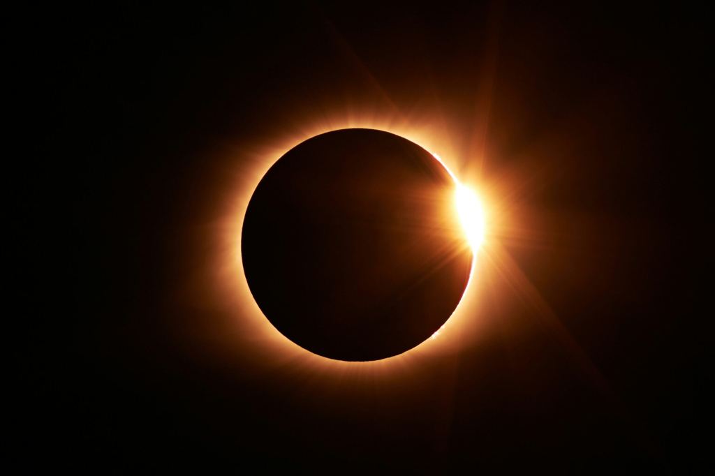 A solar eclipse with the moon almost covering the sun, leaving a bright ring and a flare of light, known as the “diamond ring” effect. - PsychDiscouse