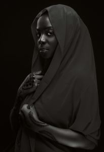 A woman with henna-decorated hands wears a draped, dark shawl over her head and shoulders, gazing forward with a calm expression against a black background. - PsychDiscouse