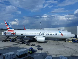 An American Airlines passenger jet parked at an airport gate being serviced by ground crew and equipment. - PsychDiscouse