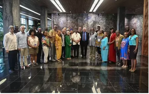 A group of people stands posed for a group photo in a large, modern indoor space with marble floors and artistic walls. - PsychDiscouse