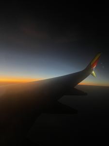 View from an airplane window showing a wing and a colorful sunset or sunrise sky with a gradient from orange to deep blue. - PsychDiscouse