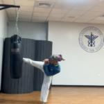 A person performs a side kick against a hanging boxing bag in a gym. - PsychDiscouse