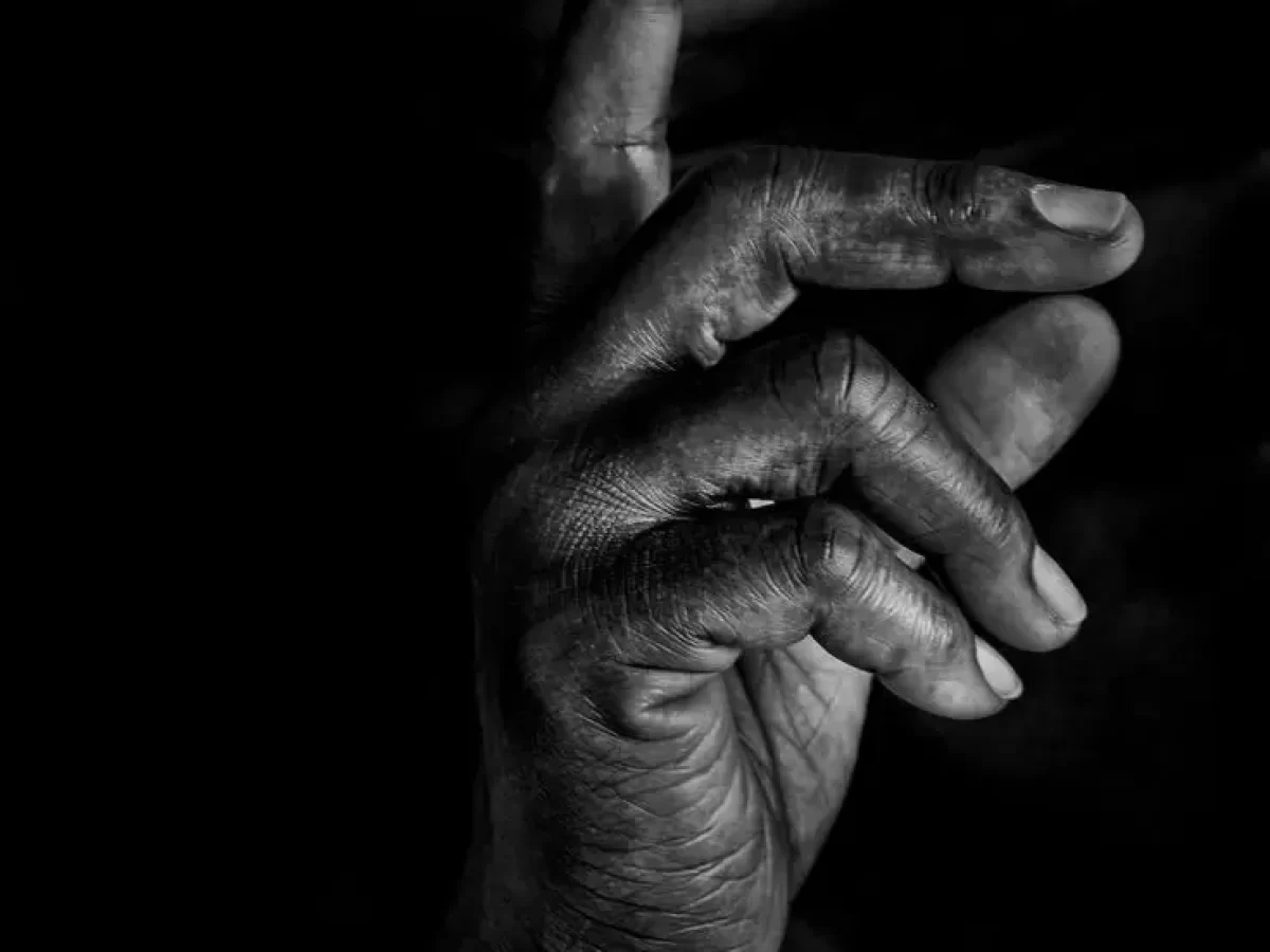 Black and white close-up of a person holding a finger to their lips in a gesture for silence. - PsychDiscouse